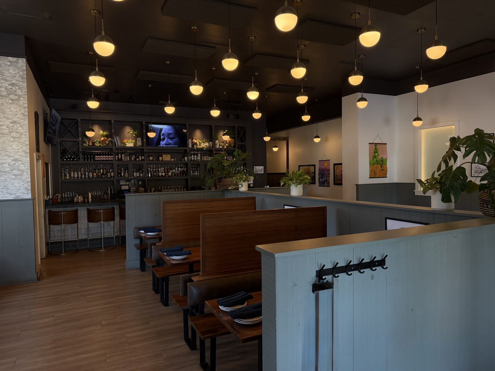 Harvest Granville dining room with globe pendant lights, wooden booths, and the back bar
